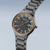 Bering Solar Armbanduhr seitlich: graues Edelstahlgehäuse mit schwarzem Zifferblatt, orange Details