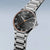 Herrenuhr mit rundem Gehäuse, schwarzem Zifferblatt, Metallgliederband und orangefarbener Lünette