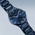 Herrenarmbanduhr Bering mit blauem Zifferblatt, Zeigern mit Leuchtpunkten und Metallgliederarmband.