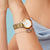 Bering Damenuhr am Handgelenk: gold-silbernes Metallarmband mit rundem weißem Zifferblatt