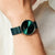 Bering Armbanduhr am Handgelenk mit grünem Milanaise-Armband und rundem Gehäuse