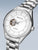 Silberne Herrenuhr mit weißem Zifferblatt und sichtbarem Automatikwerk, Metallarmband