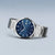 Herrenarmbanduhr seitlich: silbernes Metallarmband, blaues Zifferblatt, dezentes Branding