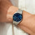 Herrenarmbanduhr am Handgelenk mit silbernem Armband und blauem Zifferblatt