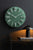 Väggklocka med rund, grön urtavla, silverfärgade timmarkeringar och visare