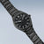Herrenuhr mit schwarzem Zifferblatt und Metallarmband, diagonale Ansicht