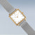 Armbanduhr im Detail: weißes Zifferblatt, goldfarbenes Gehäuse, silbernes Milanaiseband