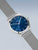 Bering Herrenarmbanduhr in Seitenansicht: blaues Zifferblatt mit Strichindizes, silbernes Meshband
