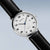 Herrenuhr Nahansicht: weißes Zifferblatt mit Indexen, silbernes Gehäuse, schwarzes Lederband