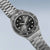Herrenarmbanduhr schrägansicht mit schwarzem Zifferblatt, geriffelter Lünette und Metallband