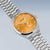 Herrklocka med orange urtavla och armband i silverfärgat rostfritt stål, sedd snett
