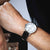 Festina herrklocka på handleden med svart läderarmband och vit urtavla