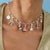 "Silversfär halsband med färgglada berlocker och Snoopy-motiv på en rosa piedestal"