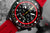 Tarcza chronografu Vostok Europe z czarnym wyświetlaczem, czerwonym pierścieniem zewnętrznym i kolorowymi oznaczeniami.