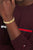 Gliederarmband med guldfärgade, texturerade länkar och liten logotyp vid handleden