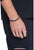 Flätat Tommy Hilfiger läderarmband runt handleden, mörkbrunt, med silverfärgad plakett med ränder
