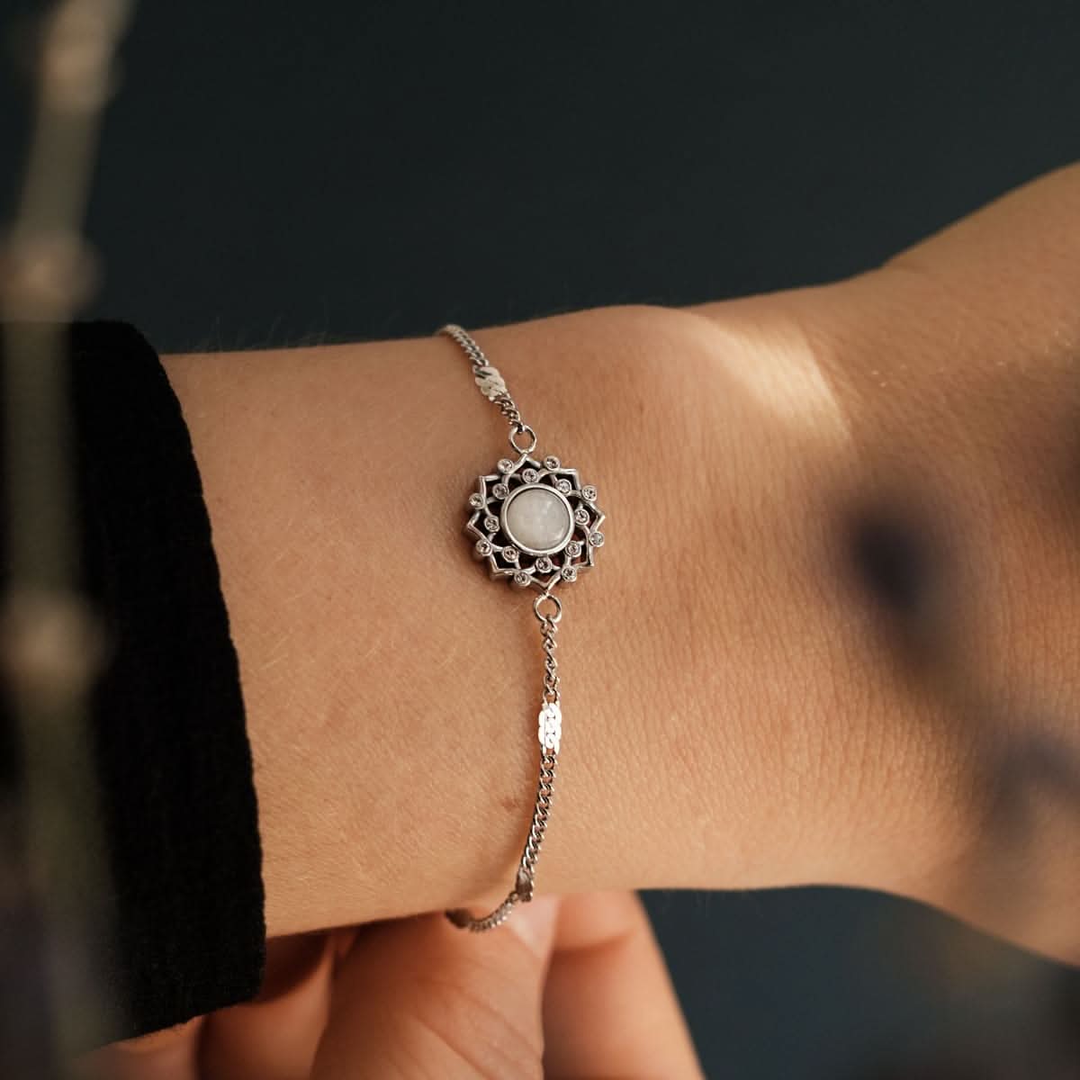 Silversmycke med rund grå cabochon i blommig ornamentik och fin kedja.