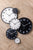 Väggklocka med vit urtavla och svart ram, bredvid andra klockor i svart/vitt