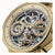 Goldfarbene Armbanduhr im Nahblick: skelletiertes Zifferblatt mit Mondphase und Dual Time