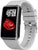 Smartklocka med rektangulär display och ljusgrå silikonrem, sedd från sidan.