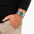 Herrklocka på handleden med grön urtavla och silverfärgat metallarmband