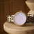 Zweifarbige Armbanduhr mit lila schimmerndem Zifferblatt und Metallarmband