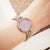 Damenarmbanduhr mit lila Zifferblatt und silber-goldenem Edelstahlarmband am Handgelenk