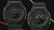 Zwei schwarze G-Shock Armbanduhren mit Resinband; eine mit grünen Leuchtmarkierungen.