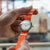 Herrklocka med orange textilarmband, rund vit urtavla