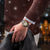 Herrenuhr am Handgelenk: schwarzes Zifferblatt mit goldenen Zeigern und Metallarmband.