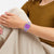 Swatch Armbanduhr am Handgelenk mit transparentem Band und violettem Zifferblatt