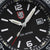 Herrklocka närbild: svart urtavla, LUMINOX-logotyp, datumfönster, självlysande visare