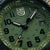"Herrenuhr-Detail: rundes grünes Zifferblatt mit Leuchtmarkierungen und Zeigern"