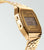 Guldtonad Casio Vintage-klocka med metallarmband, boett sedd från sidan och LCD-display med larm.