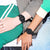 Svart digital sportklocka på två handleder med gummiband.