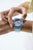"Damenuhr am Handgelenk, transparentes türkisfarbenes Armband und graues Gehäuse"