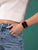 Smartklocka med rött armband runt handleden, svart fyrkantig display