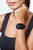 Smartklocka på handleden: svart urtavla, svart armband, blå dekorerad ring.