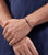 "Grått armband runt handleden med fin länkkedja och litet logohänge"