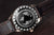 Herrarmbandsur med världskartmotiv på baksidan av boetten och brunt läderarmband