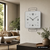 Wanduhr an der Wand mit grauer Front, schwarzen Ziffern und Zeigern